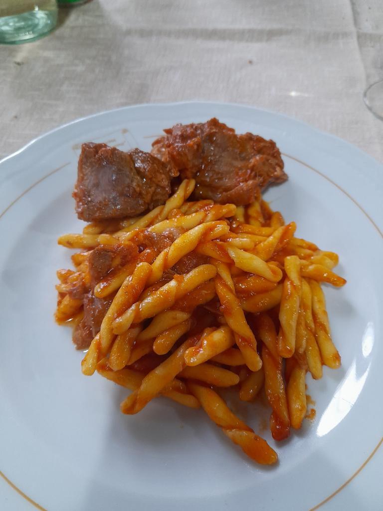 Plate of handmade fileja pasta tossed in rich red tomato ragù with tender braised meat.